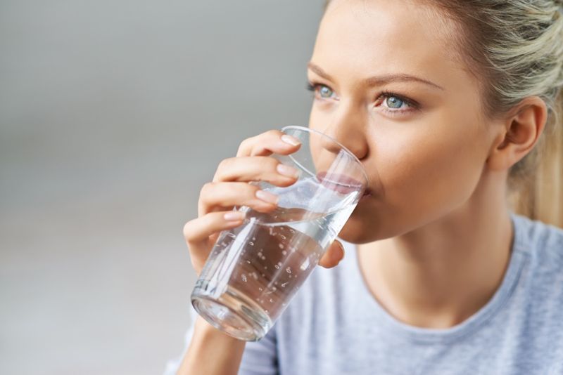 امرأة تشرب الماء من الزجاج.'