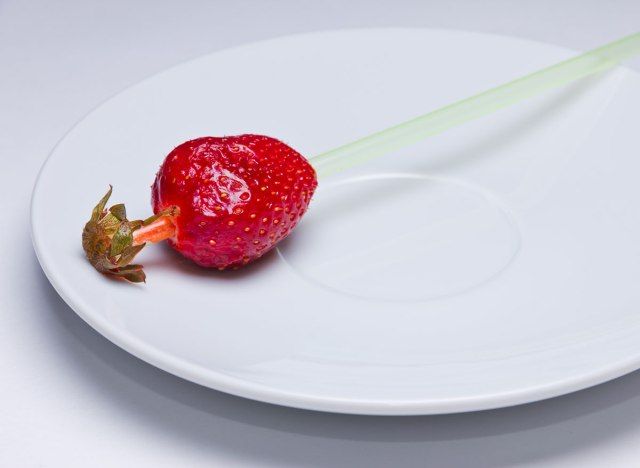 فراولة مقشرة مع شفاط من خلالها على طبق.'