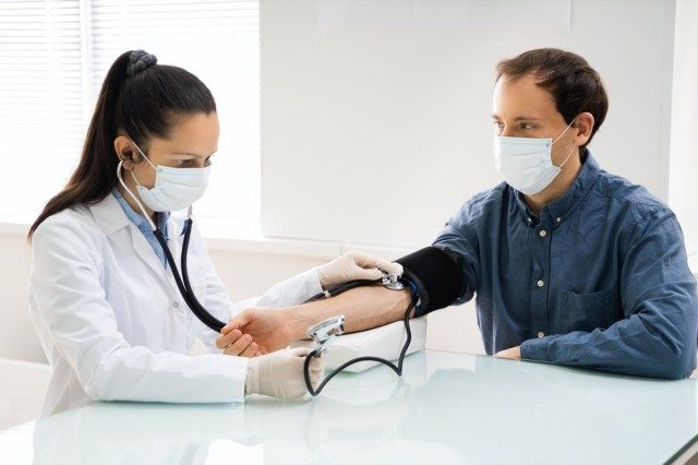 طبيب يقوم بفحص ارتفاع ضغط الدم في قناع الوجه'