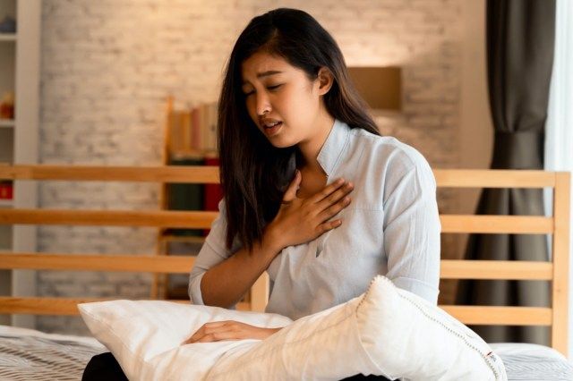 امرأة آسيوية تواجه صعوبة في التنفس في غرفة النوم ليلا'