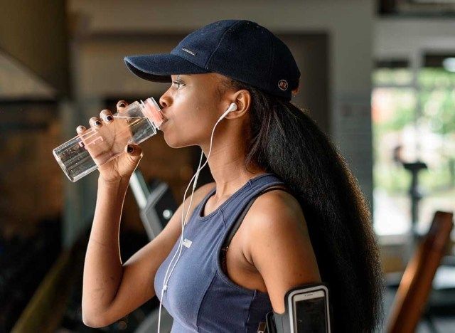 امرأة تشرب الماء في صالة الألعاب الرياضية'