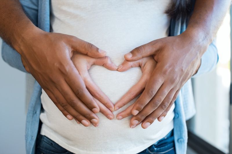 رجل أسود يحمل بطن زوجته الحامل صنع القلب'