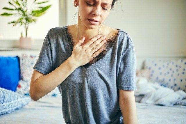 امرأة تعاني من آلام في الصدر أثناء جلوسها في المنزل'