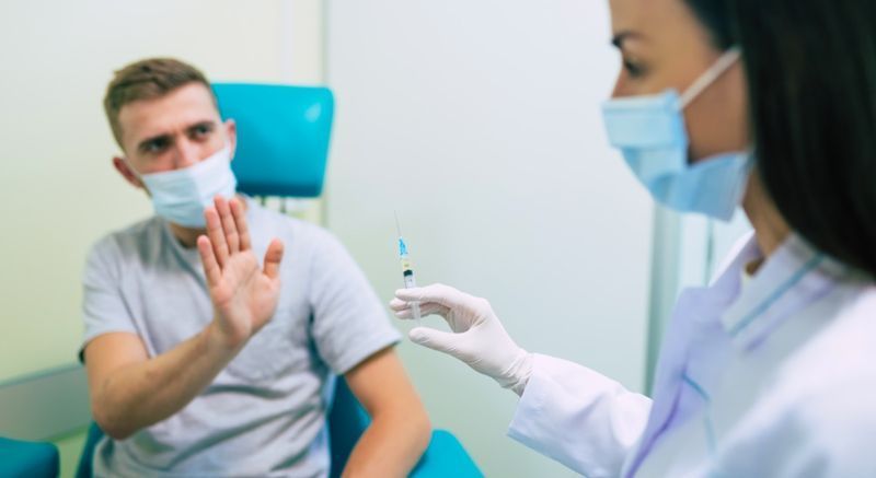 رجل يشير إلى الممرضة وهو يعرض حقنة مع اللقاح.'