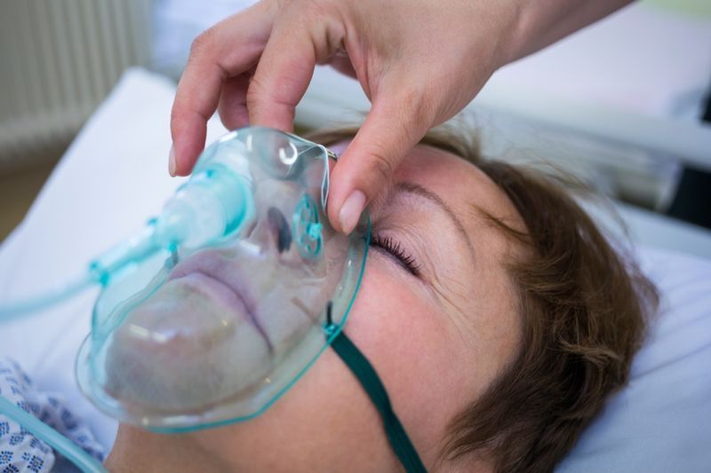 ممرضة تضع قناع أكسجين على وجه مريض في المستشفى.'