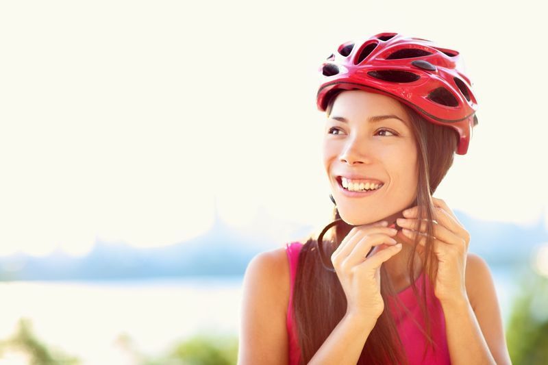 امرأة تضع خوذة ركوب الدراجات في الخارج أثناء ركوب الدراجة'