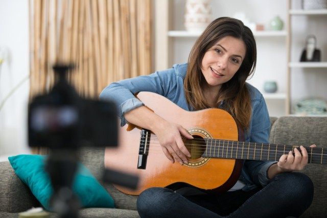 امرأة تسجل مدونة موسيقية باستخدام الغيتار'