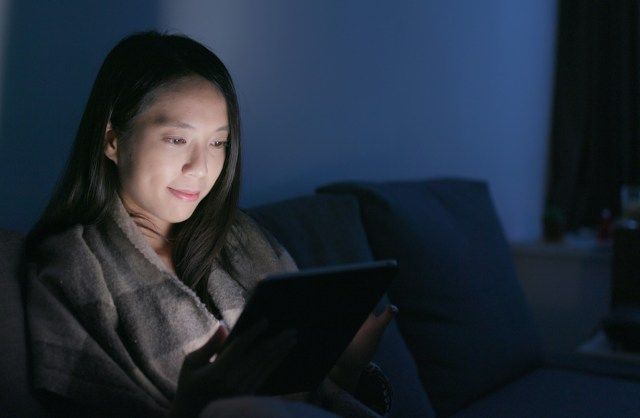 امرأة تنظر إلى الكمبيوتر اللوحي في المنزل'
