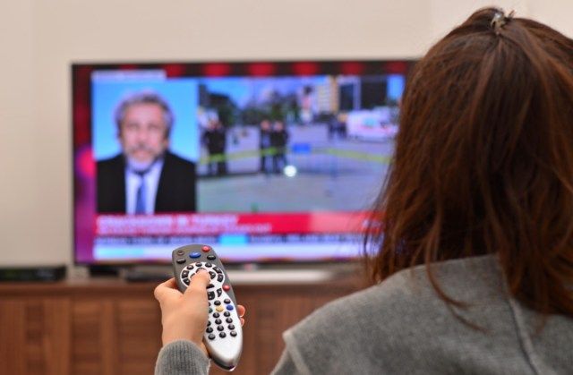 النساء يشاهدن التلفاز ويستخدمن جهاز التحكم عن بعد'