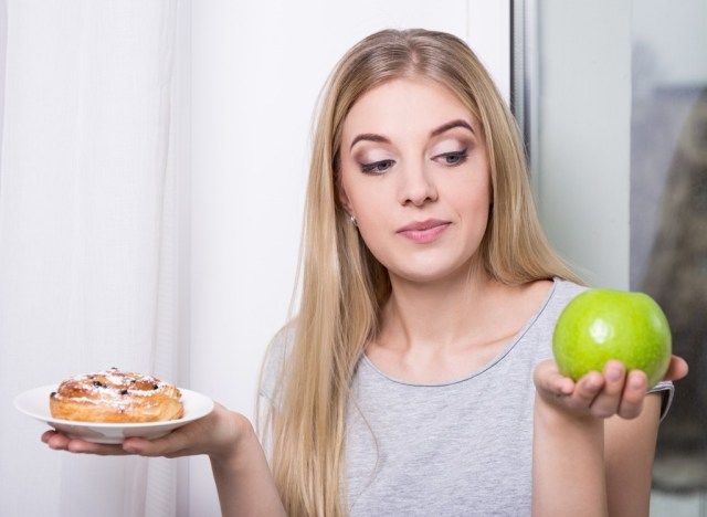 امرأة تختار التفاح على المعجنات المليئة بالسكر'