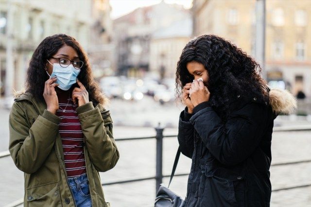 مع العطس في شارع المدينة ، امرأة بدون قناع واقي أثناء انتشار الأنفلونزا ، البرد ، كوفيد -19'