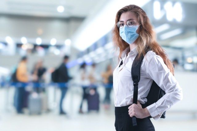 قناع الفيروس الذي تسافر امرأة ترتدي حماية الوجه في الوقاية من فيروس كورونا في المطار.'