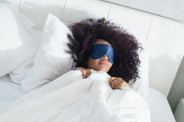 امرأة نائمة في الفراش مع قناع العين'