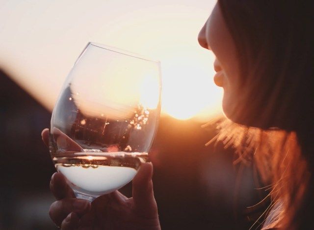 امرأة تشرب الخمر الأبيض عند غروب الشمس'