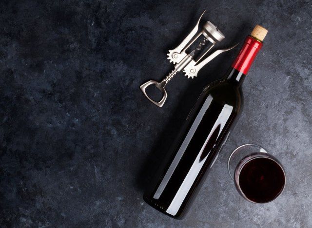 زجاجة من بقايا النبيذ الأحمر على سطح طاولة مظلم'