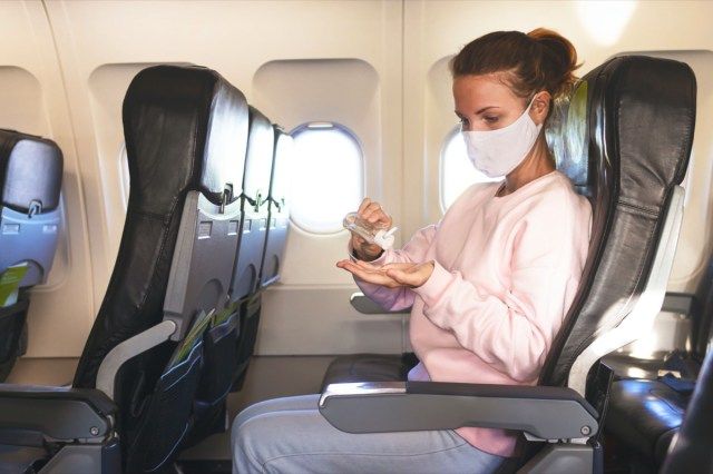 امرأة في الطائرة تطهر اليدين بالجيل والمطهر أثناء الطيران'