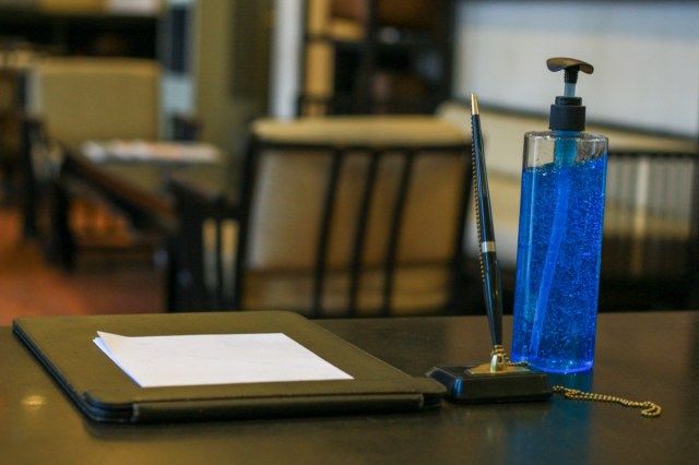 استمارة تسجيل الفندق التي تحتوي على هلام كحولي أزرق تستعد للضيف لتنظيف اليد قبل التسجيل'