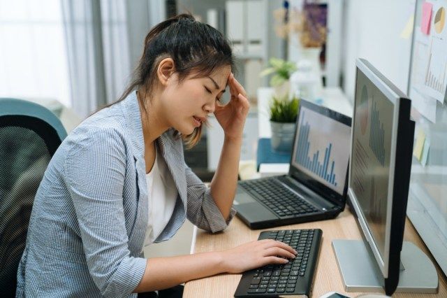 مرهقة محبطة محبطة سيدة أعمال آسيوية تقرأ بريدًا إلكترونيًا سيئًا أخبار الإنترنت على الكمبيوتر ، تشعر بالحزن والتعب'
