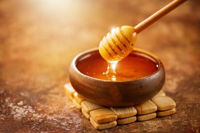 العسل يقطر من العسل في وعاء خشبي'