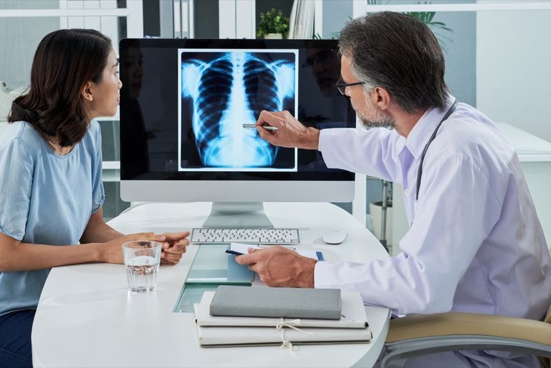 طبيب يشرح صورة الأشعة السينية للرئتين على شاشة الكمبيوتر للمريض'