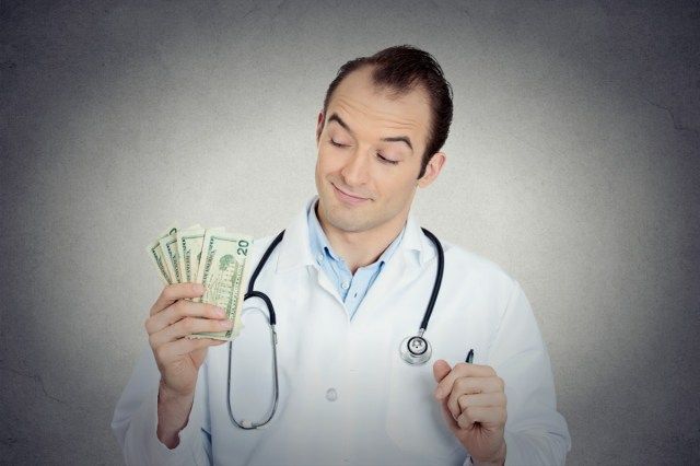 صورة لأخصائي رعاية صحية ، طبيب ذكر يحمل أموالًا في يده'