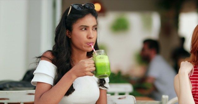 امرأة تشرب عصير أخضر صحي في الهواء الطلق'