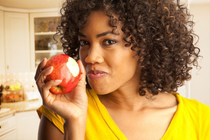 امرأة تأكل التفاح الأحمر الطازج داخل البيت kitchen'
