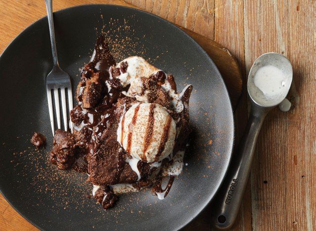 كعكة الشوكولاتة مولتن لافا الكرز مع الزبادي المثلج وملعقة على طبق أسود'
