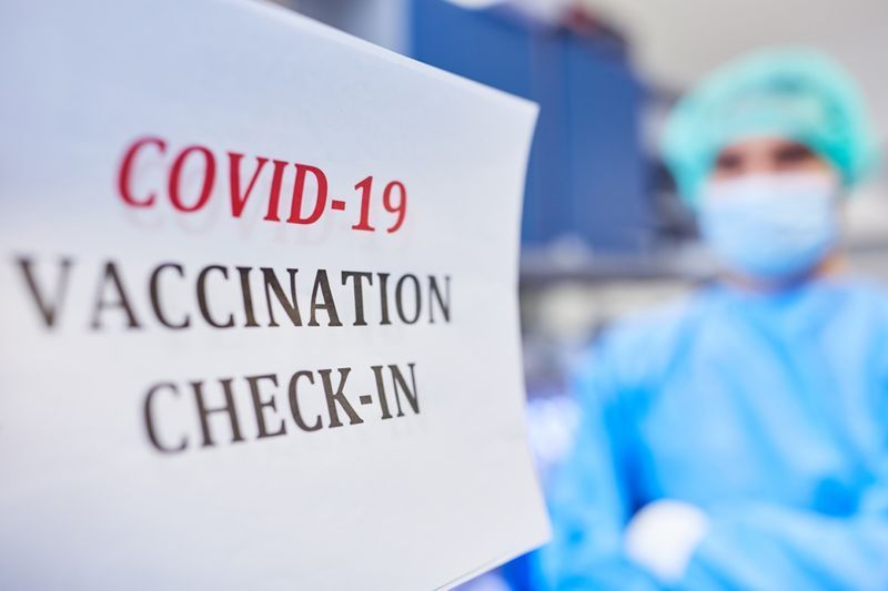 تحقق من لقاح فيروس كورونا ضد Covid-19 مع وجود طبيب في الخلفية.'