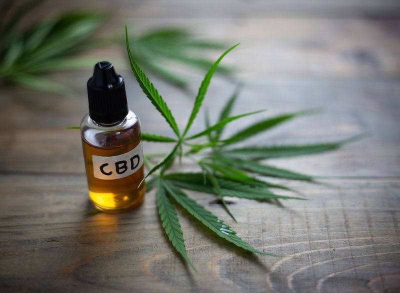 زجاجة زيت cbd بجانب أوراق الماريجوانا'