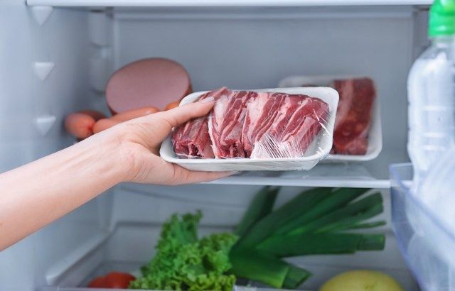 امرأة تضع اللحم النيء في الثلاجة'