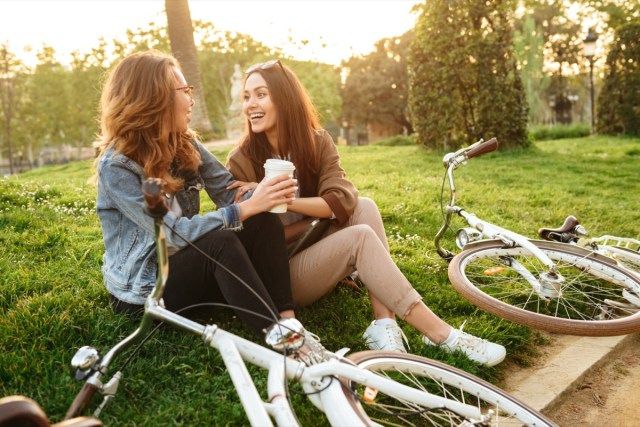 صورة اثنين من النساء الشابات الجميلات الأصدقاء في الهواء الطلق مع الدراجات في الحديقة.'