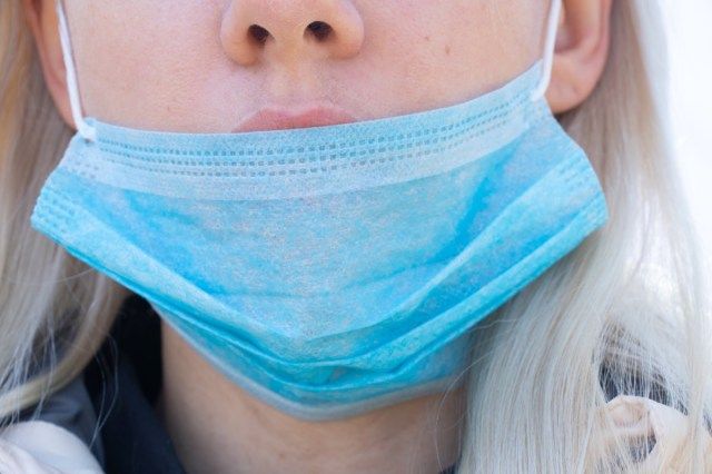 امرأة ترتدي قناعًا طبيًا على وجهها أثناء انتشار الوباء في الهواء الطلق'