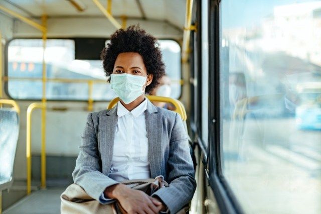 sinesswoman يرتدون قناعا واقيا أثناء السفر بالمواصلات العامة.'