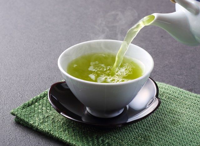 يتم سكب الشاي الأخضر في فنجان الشاي الأبيض'