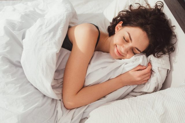   امرأة تنام بسعادة في سرير قطيفة