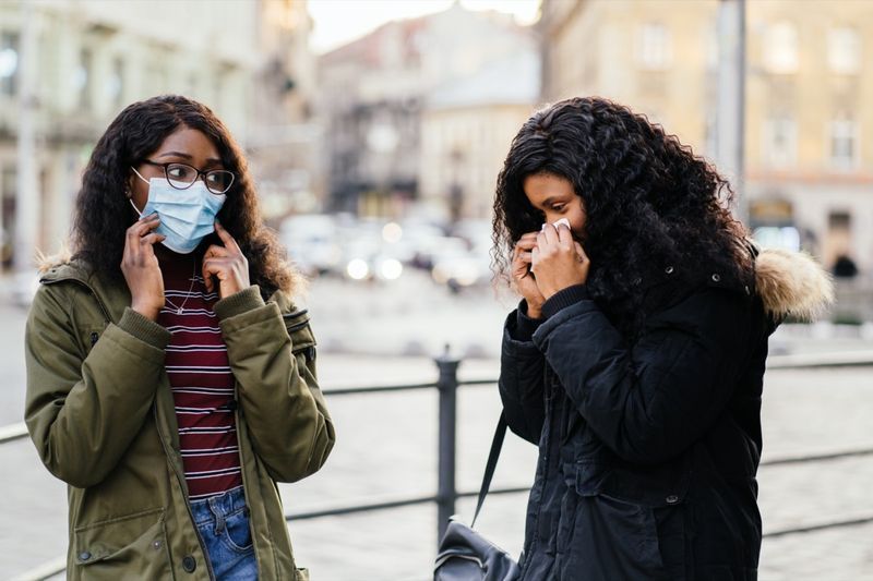 مع العطس في شارع المدينة ، امرأة بدون قناع واقٍ أثناء انتشار الأنفلونزا ، البرد ، كوفيد -19'