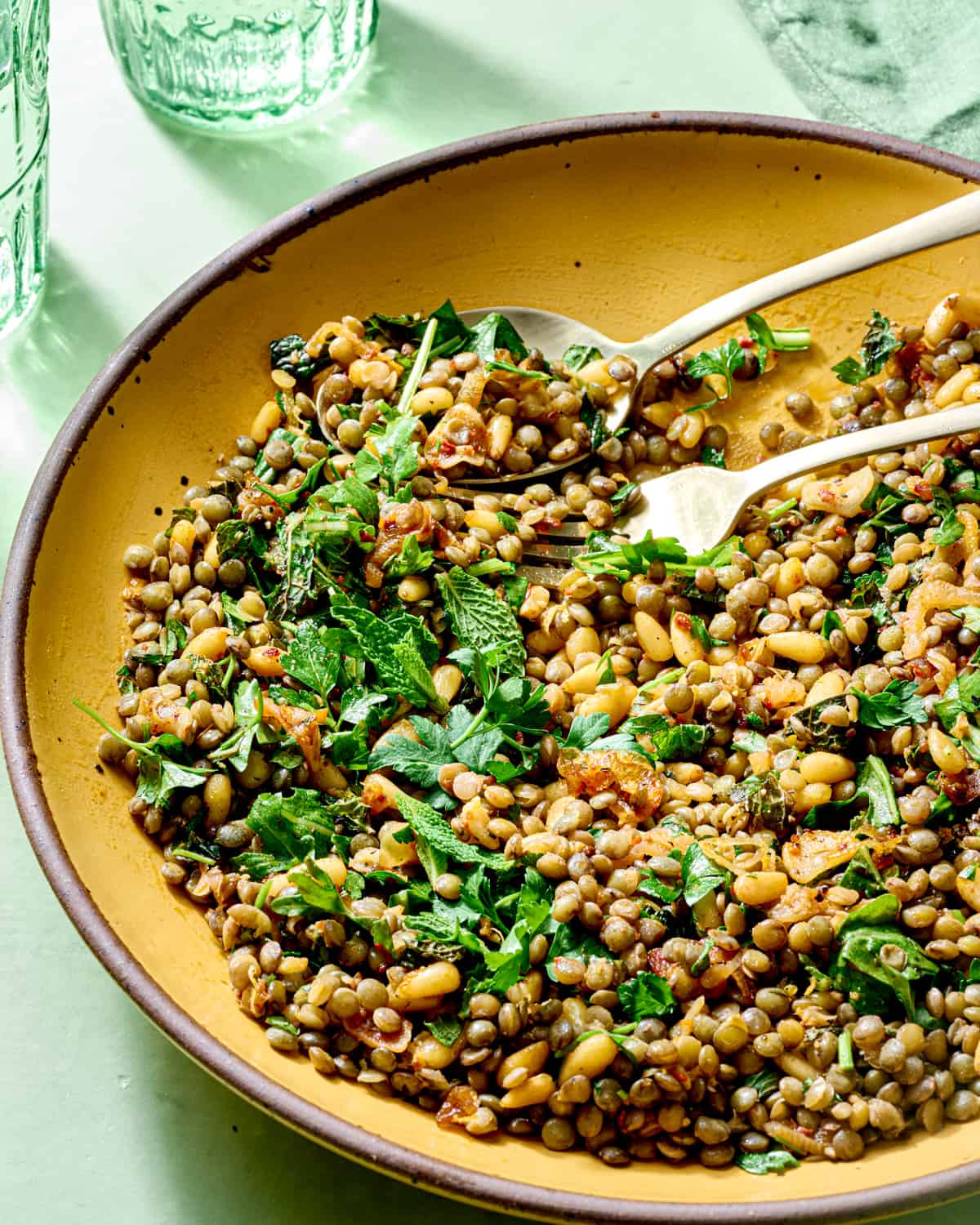 Close up of lentil salad with herbs in yellow bowl.