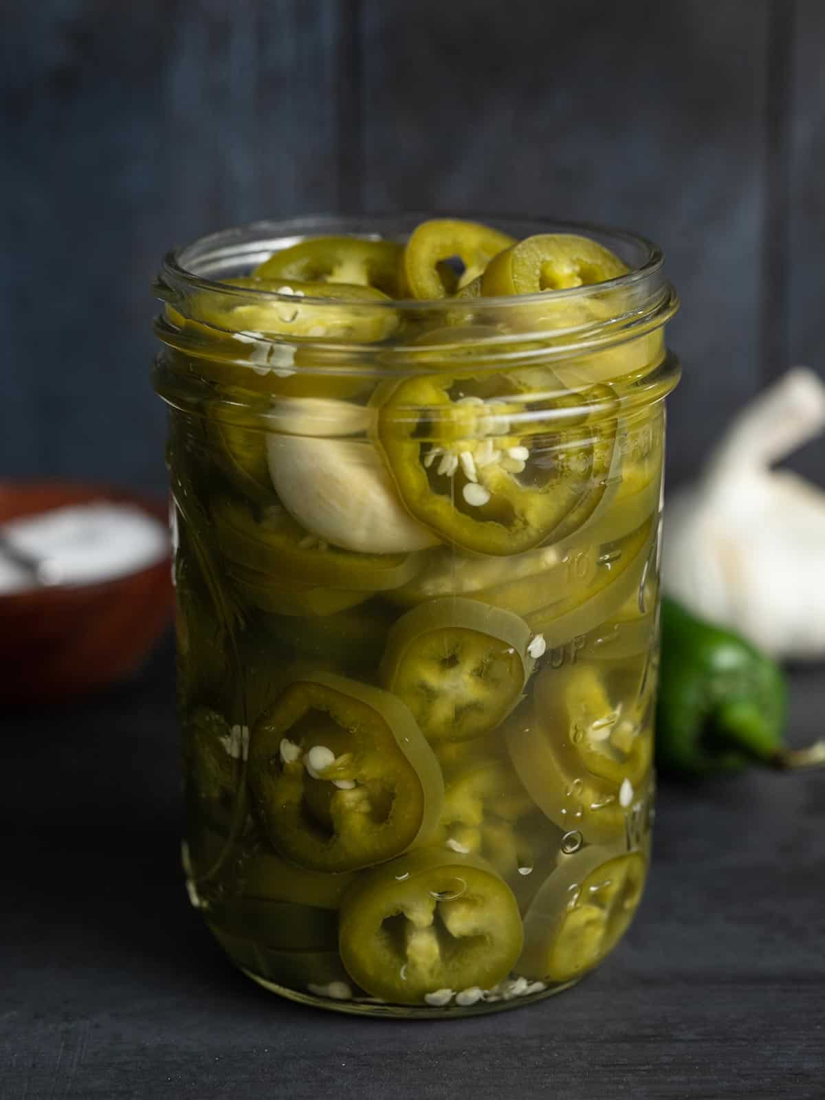 Side view of pickled jalapeños in a jar.