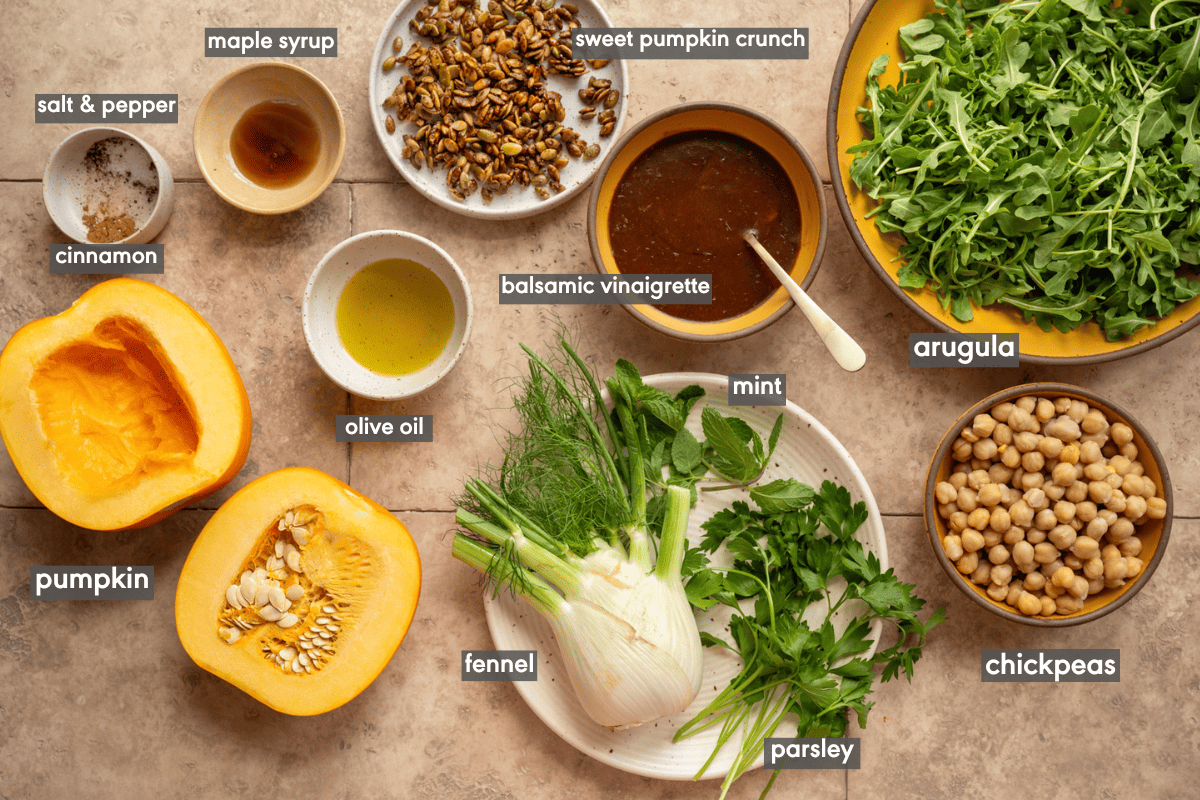Pumpkin salad ingredients on various plates and bowls on a table.