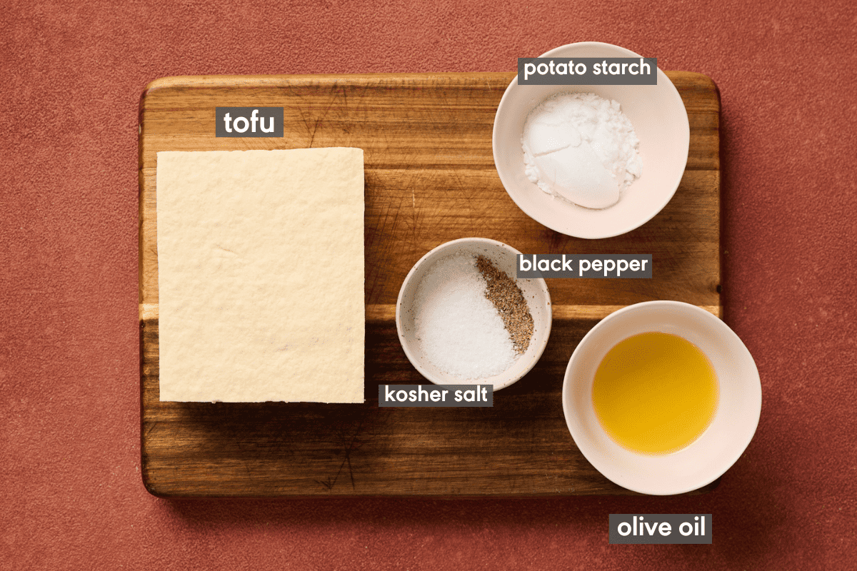 Baked tofu ingredients in small bowls on a wooden cutting board.