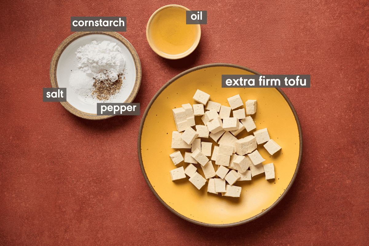 Fried tofu ingredients in bowls on a red table.