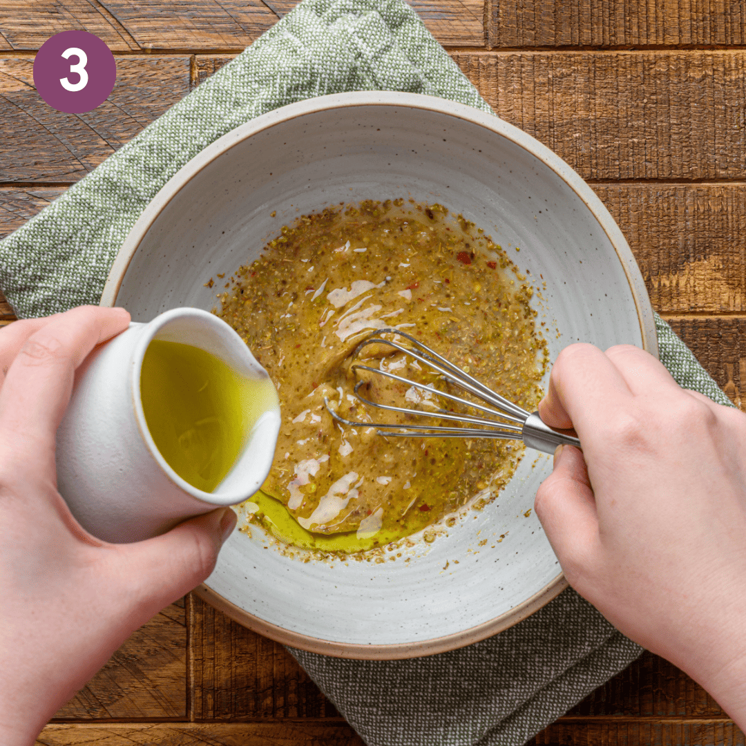 person pouring oil into rest of vinaigrette ingredients.